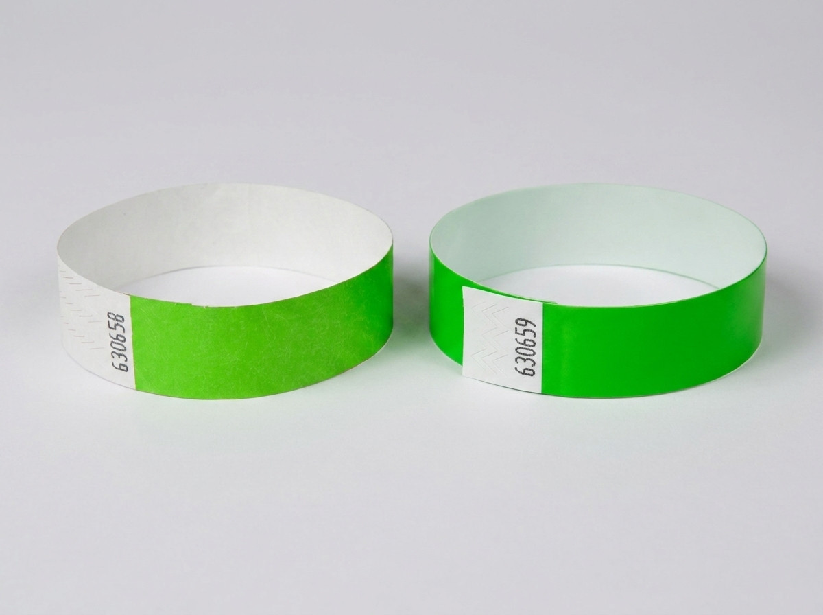 Vergleich eines weißen Tyvek-Armbands mit gedrucktem Barcode und eines farbigen Identifikationsarmbands mit Barcode, auf einem Festivaltisch liegend