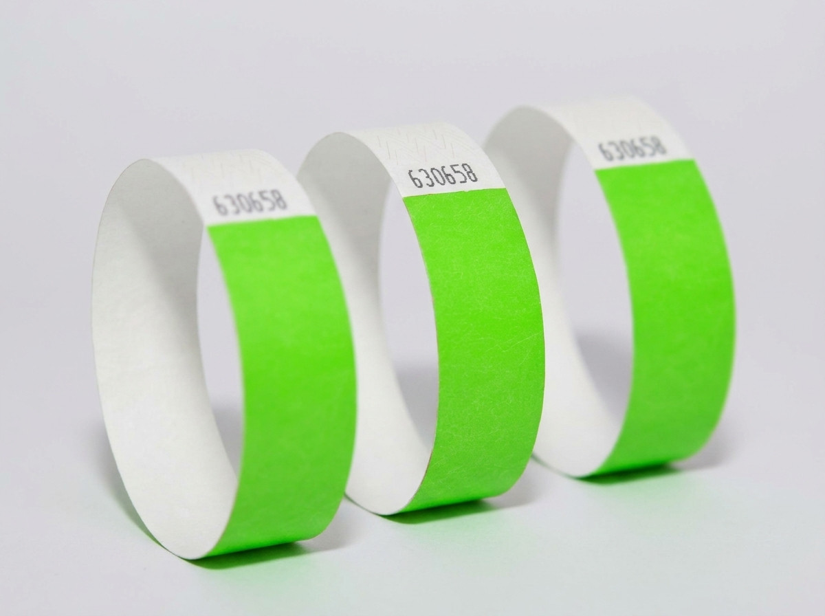 Seitenweiser Vergleich eines farbigen Tyvek-Armbands und eines eleganten weißen Identifikationsarmbands auf hellem Holzhintergrund