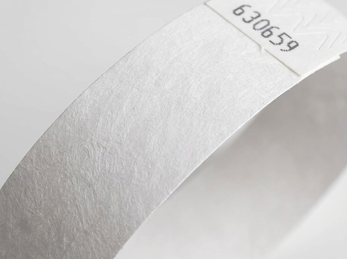Nahaufnahme der Vliesoberflaeche eines weissen Tyvek-Armbands, die die charakteristische Textur des hochdichten Polyethylens zeigt